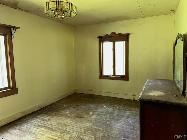 unfurnished room with a chandelier and wood-type flooring