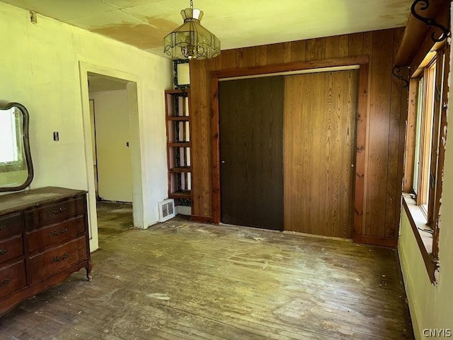 interior space featuring dark hardwood / wood-style flooring, an inviting chandelier, a closet, and wood walls