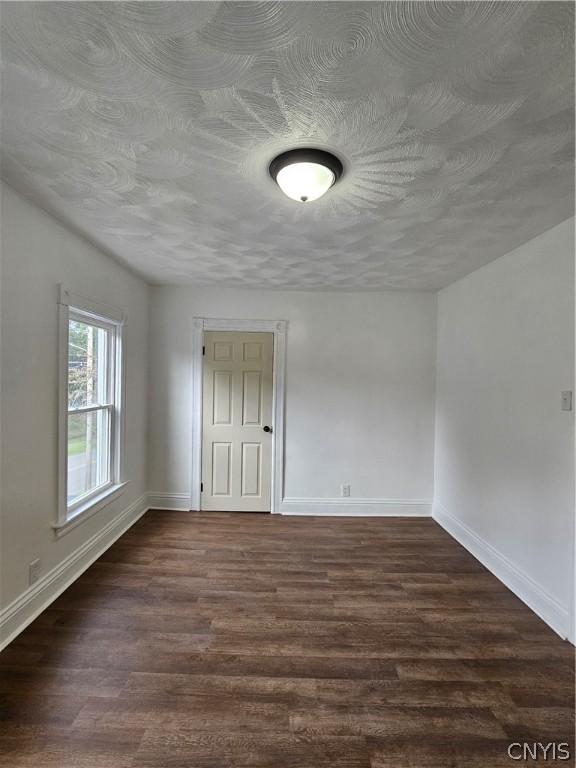 empty room with a textured ceiling and dark hardwood / wood-style flooring