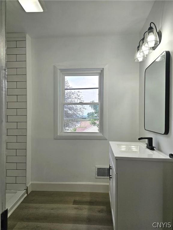 bathroom with wood-type flooring, vanity, and a shower