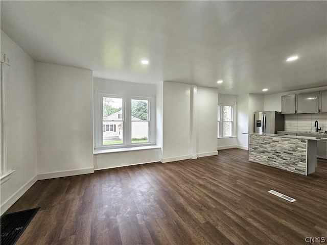 unfurnished living room featuring dark wood-type flooring and sink