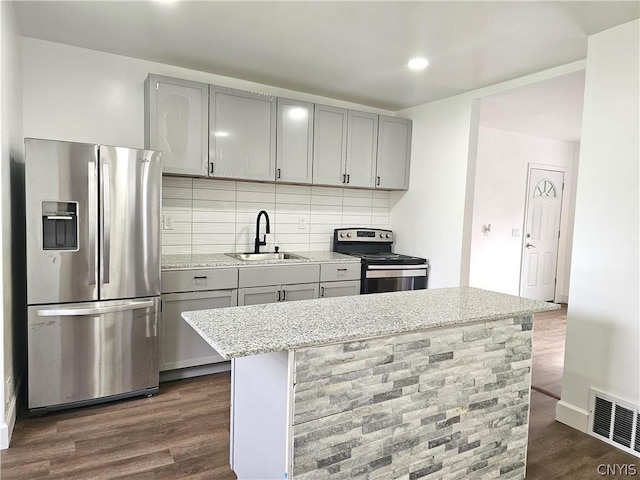 kitchen featuring sink, gray cabinetry, light stone counters, a kitchen island, and stainless steel appliances