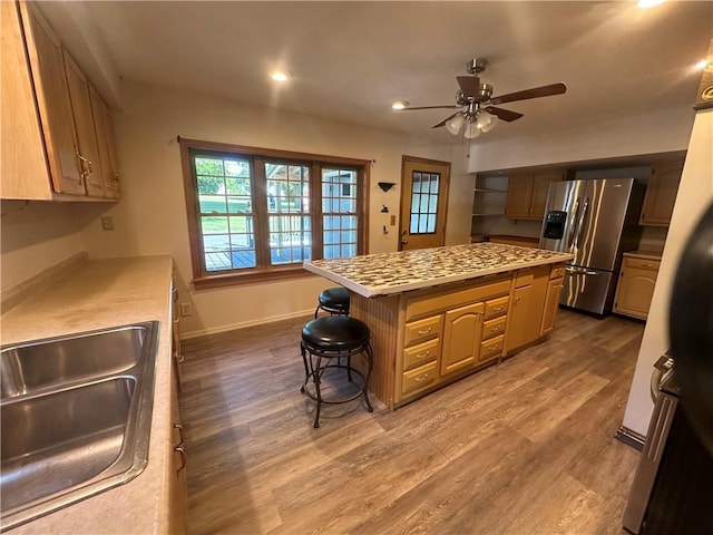 kitchen featuring a center island, sink, dark wood-type flooring, stainless steel refrigerator with ice dispenser, and a kitchen bar