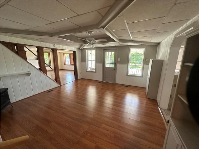 unfurnished living room featuring ceiling fan, a drop ceiling, and wood-type flooring