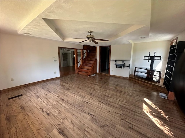 unfurnished living room featuring a tray ceiling, ceiling fan, and hardwood / wood-style flooring