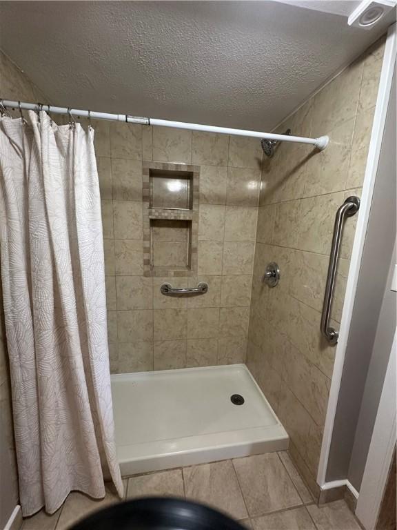 bathroom featuring tile patterned flooring, a shower with curtain, and a textured ceiling