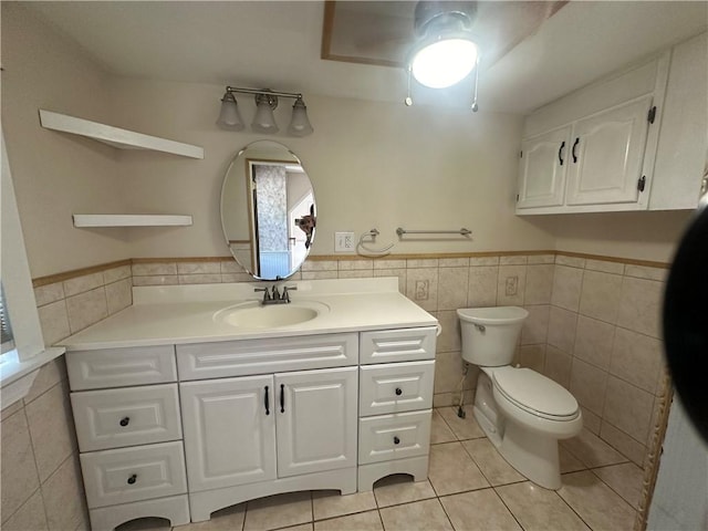 bathroom with toilet, vanity, tile patterned floors, and tile walls