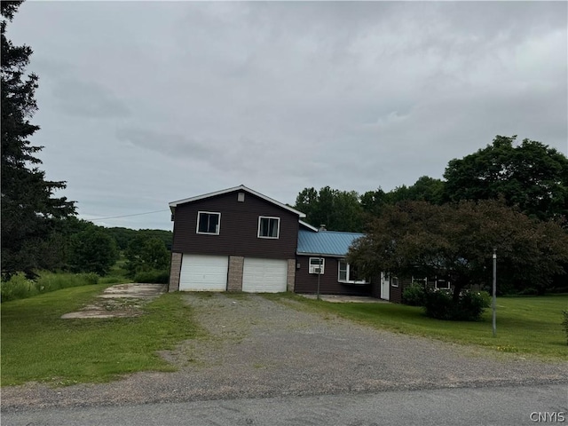 view of home's exterior with an attached garage, a yard, metal roof, and driveway