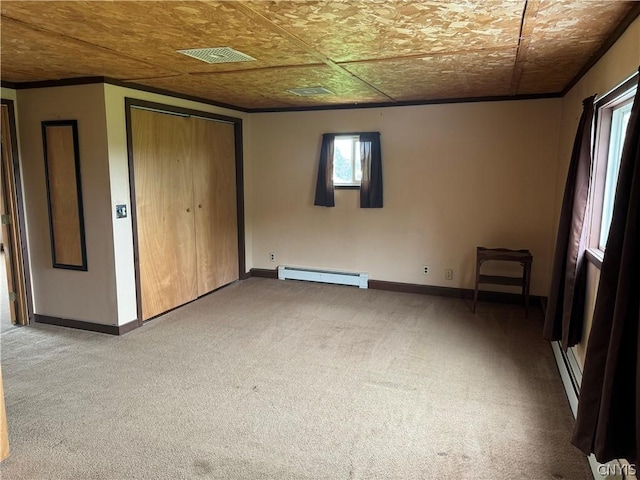 unfurnished bedroom with baseboard heating, visible vents, baseboards, and carpet