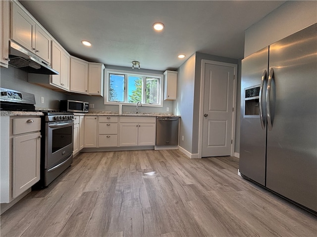 kitchen featuring white cabinets, sink, stainless steel appliances, light stone countertops, and light hardwood / wood-style floors