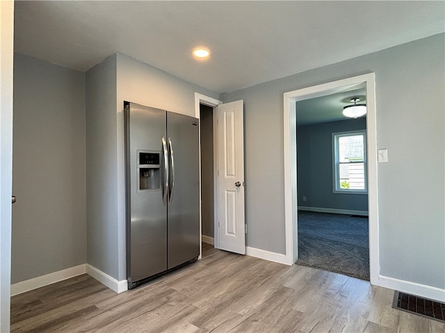 kitchen with light wood-type flooring and stainless steel fridge with ice dispenser