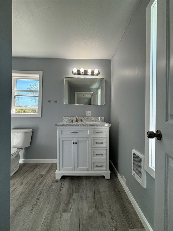 bathroom with wood-type flooring, vanity, toilet, and heating unit