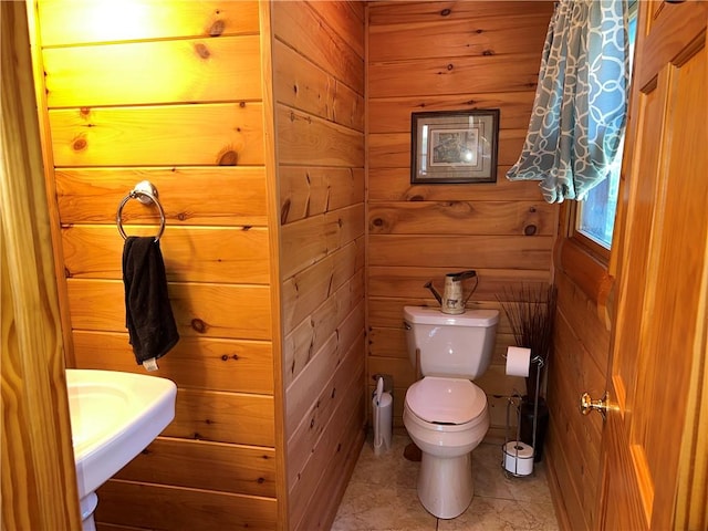 bathroom featuring tile patterned flooring, toilet, and wood walls