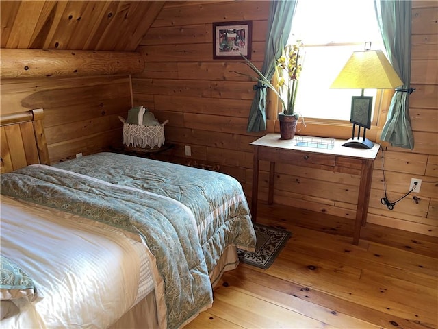 bedroom with wood-type flooring, lofted ceiling, and wood walls