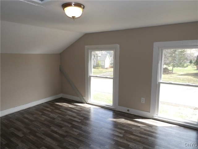 additional living space featuring dark wood-style flooring, baseboards, and vaulted ceiling
