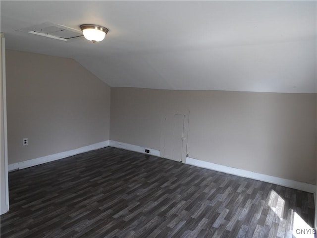 additional living space featuring baseboards, lofted ceiling, and dark wood-style floors