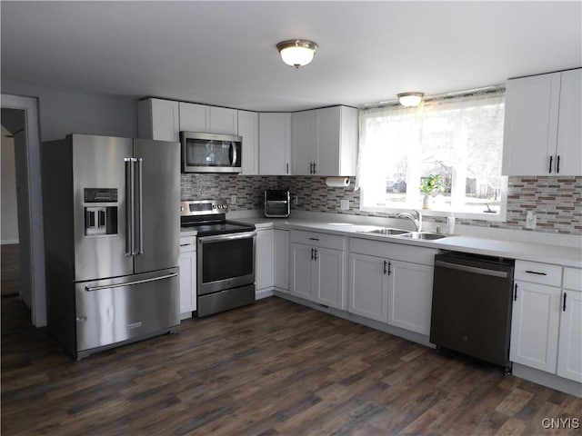 kitchen featuring a sink, backsplash, appliances with stainless steel finishes, and dark wood-style floors