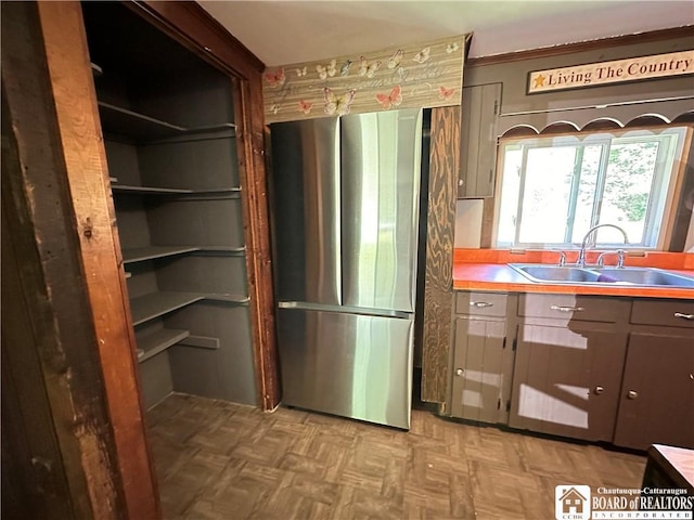 kitchen featuring stainless steel fridge, sink, and parquet floors