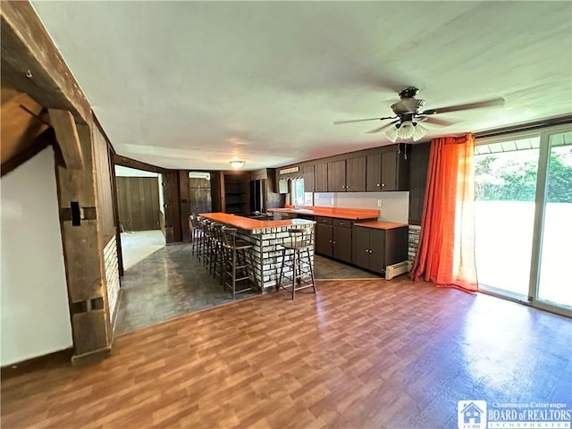 kitchen with butcher block counters, ceiling fan, light hardwood / wood-style flooring, a baseboard heating unit, and dark brown cabinets