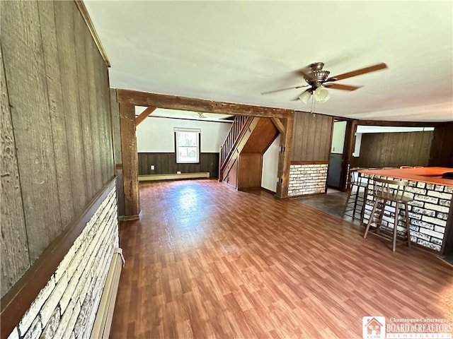 additional living space with ceiling fan, dark hardwood / wood-style floors, wooden walls, and a baseboard radiator