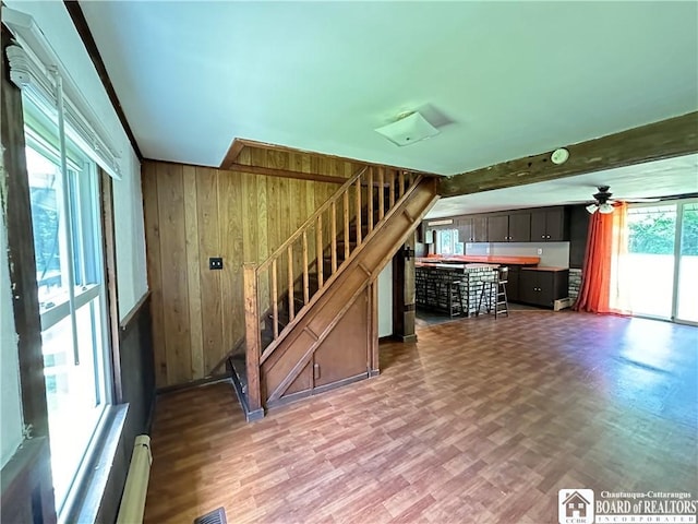 unfurnished living room with ceiling fan, wood walls, and wood-type flooring