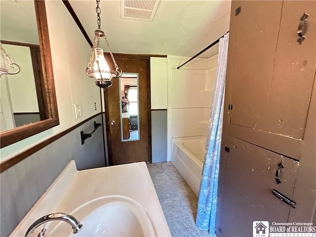 bathroom featuring sink, wooden walls, and shower / tub combo with curtain