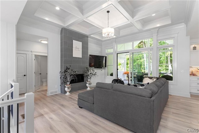 living room featuring ornamental molding, an inviting chandelier, coffered ceiling, and light hardwood / wood-style floors