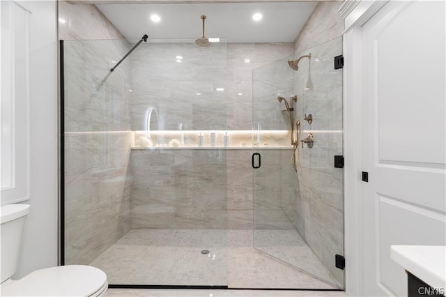 bathroom featuring a shower with shower door, vanity, and toilet