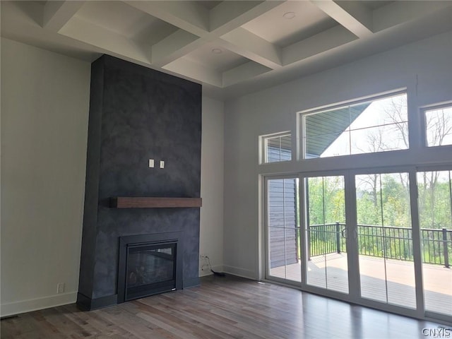 unfurnished living room featuring beam ceiling, wood-type flooring, a large fireplace, and coffered ceiling