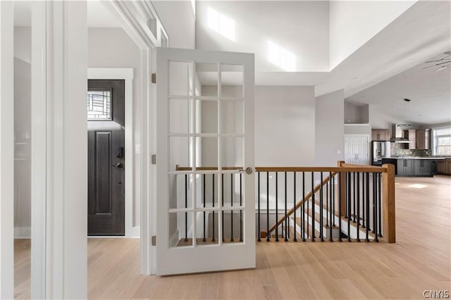 hall with light wood-type flooring and a high ceiling