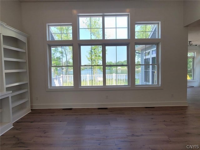 unfurnished room featuring a water view, plenty of natural light, and dark hardwood / wood-style floors