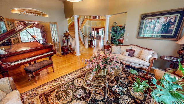 living room featuring stairs, wood finished floors, and ornate columns