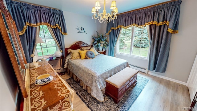 bedroom with a baseboard radiator, multiple windows, light wood finished floors, and an inviting chandelier