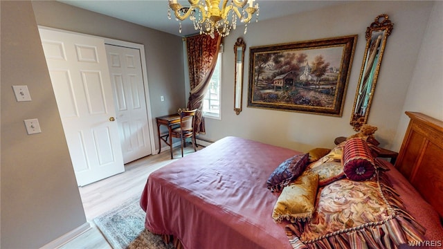 bedroom with light wood finished floors, baseboards, baseboard heating, and a notable chandelier