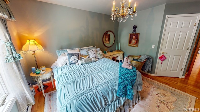 bedroom featuring a notable chandelier, baseboards, and wood finished floors