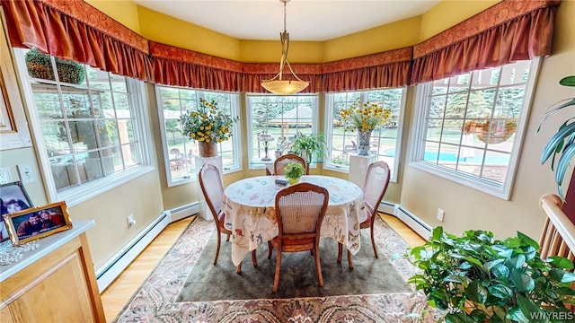 dining room featuring light wood-style floors, a baseboard radiator, and baseboards