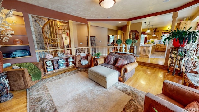 living area featuring a textured ceiling, wood finished floors, and decorative columns