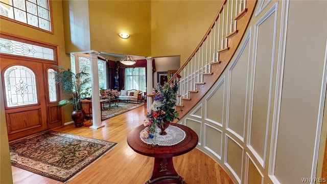 foyer featuring decorative columns, a high ceiling, stairway, and wood finished floors