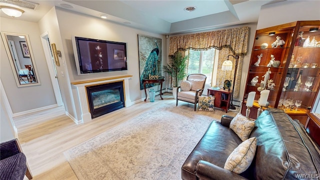 living room featuring visible vents, wood finished floors, and a glass covered fireplace