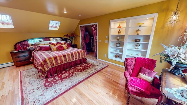 bedroom featuring vaulted ceiling with skylight, a baseboard radiator, a spacious closet, and wood finished floors