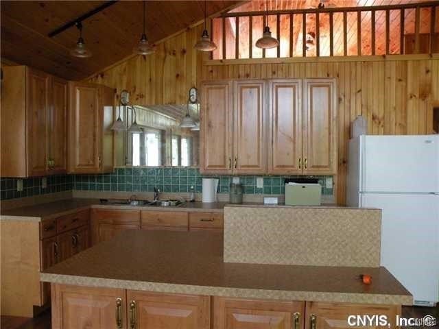 kitchen featuring sink, white fridge, vaulted ceiling, and backsplash