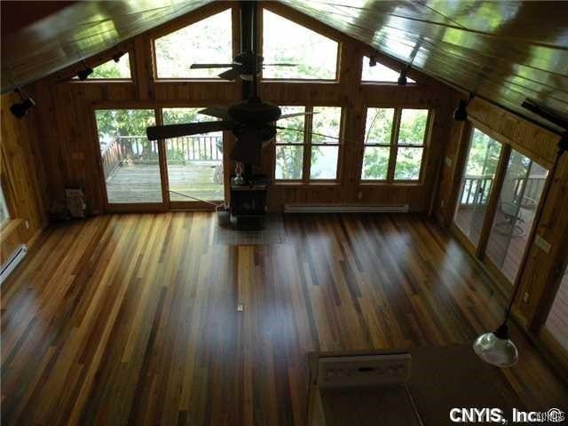 unfurnished living room with wood-type flooring, wooden walls, and lofted ceiling