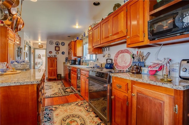 kitchen with light stone counters, light hardwood / wood-style flooring, and electric range