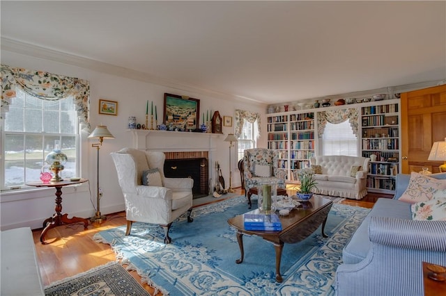 living room featuring crown molding, hardwood / wood-style floors, and a brick fireplace