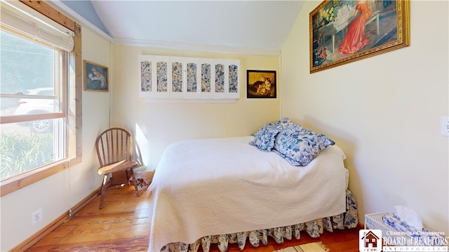 bedroom featuring hardwood / wood-style flooring, multiple windows, and vaulted ceiling