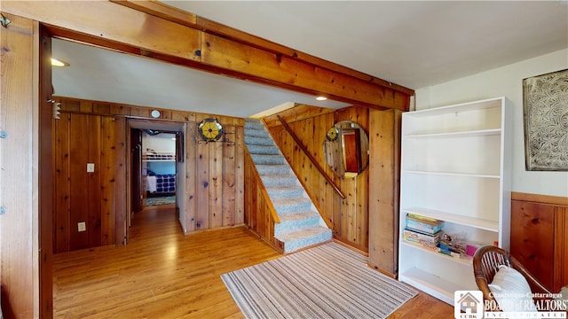 interior space with beamed ceiling, light hardwood / wood-style flooring, and wood walls