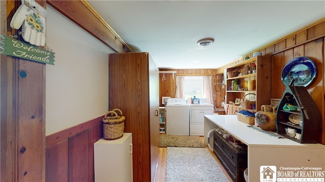 hall with wooden walls, washer and dryer, and light carpet