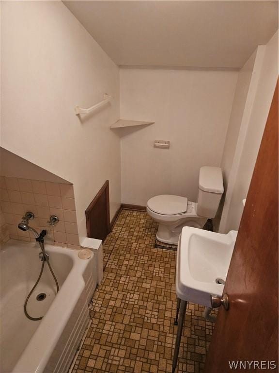 bathroom with toilet, sink, and a tub to relax in