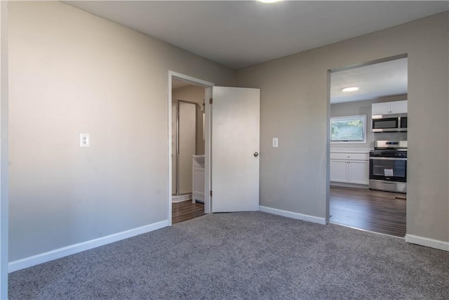 unfurnished bedroom featuring dark carpet and ensuite bathroom