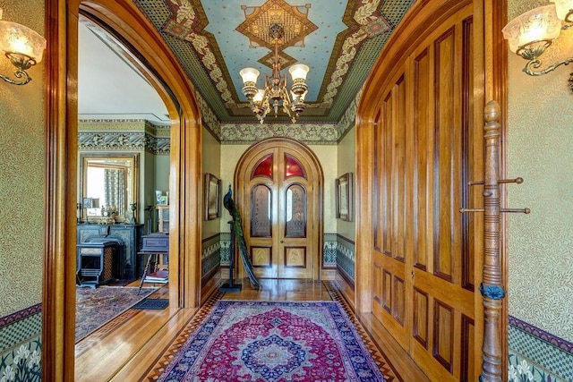 73 Elm St, Otsego, NY 13326 - entryway with crown molding, wood finished floors, wallpapered walls, arched walkways, and an inviting chandelier